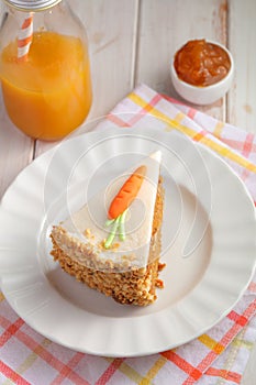 Slice of carrot cake  Pastel de zanahoria with icing and marzipan carrot on white background with carrot juice photo